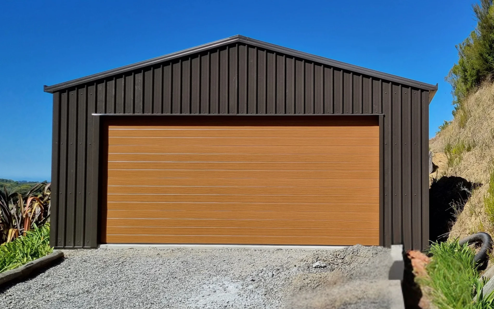 6.0m x 6.0m double garage, featuring 6-Rib Corrugate cladding in COLORSTEEL® Ironsand, paired with a NatureSteel door
