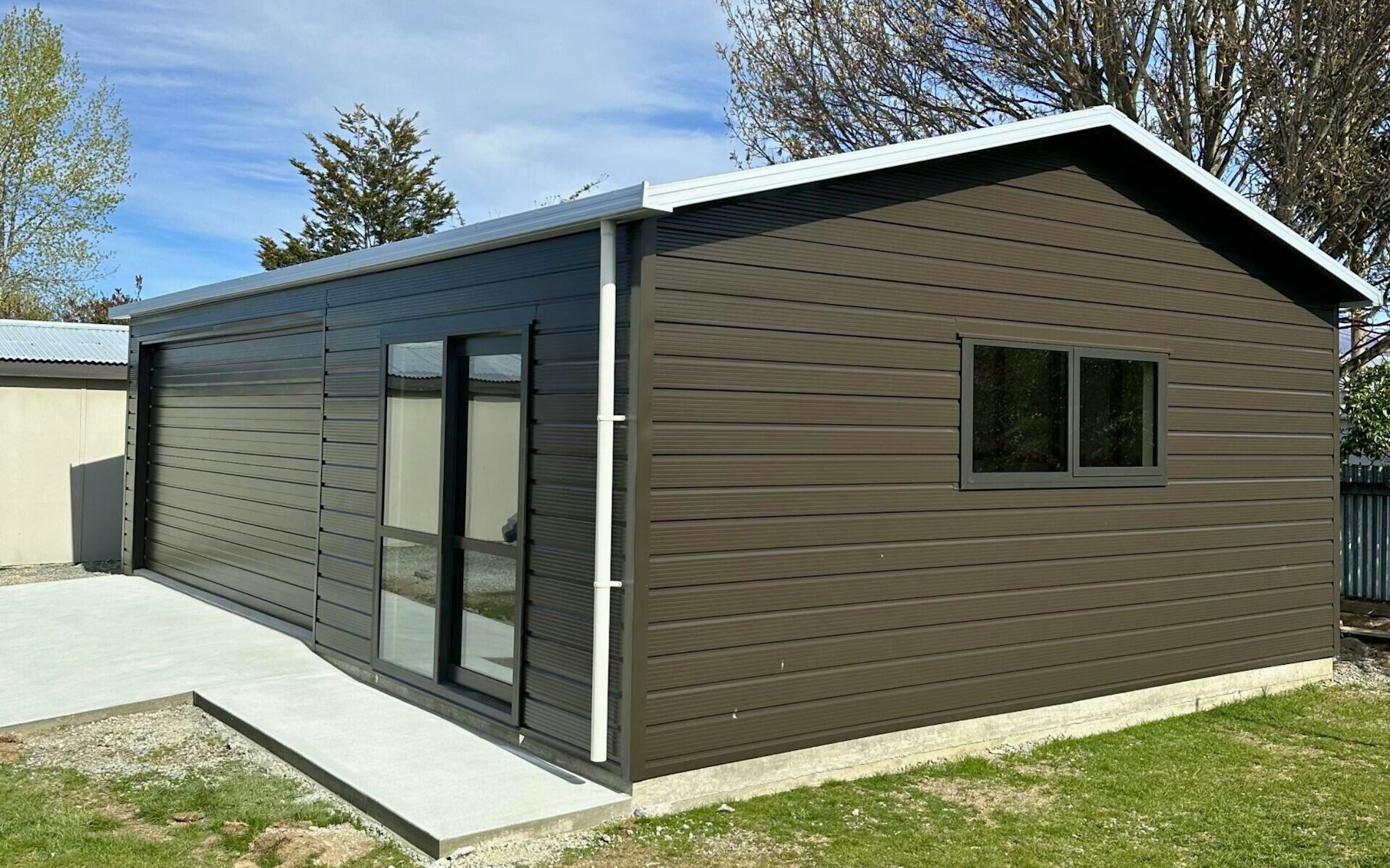 9m x 6m double garage and extra room, Superclad cladding  in COLORSTEEL® Ironsand and Sectional door 4.8m wide and Aluminium Joinery Ironsand