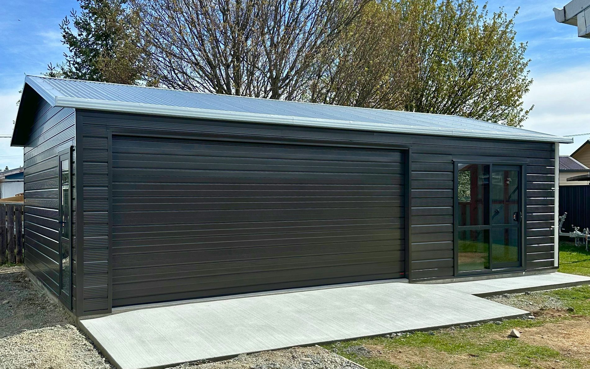 9m x 6m double garage and extra space, Superclad cladding  in COLORSTEEL® Ironsand and Sectional door 4.8m wide and Aluminium Joinery Ironsand