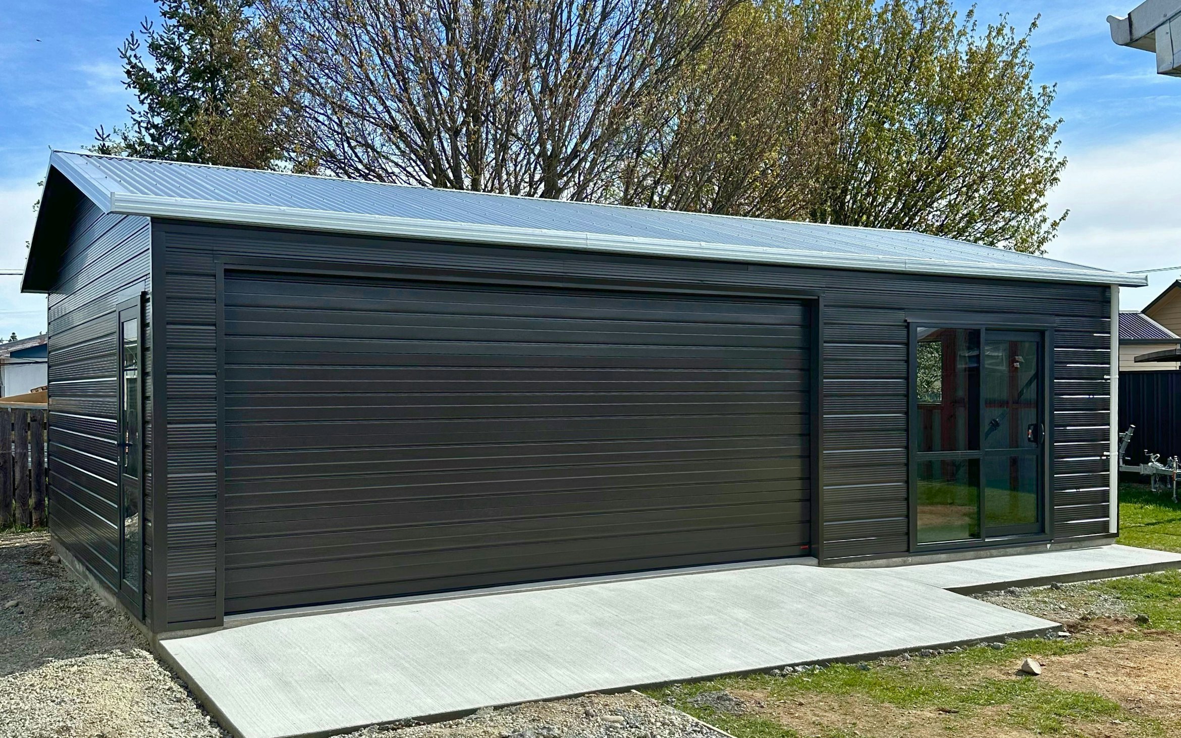 9m x 6m double garage and extra space, Superclad cladding  in COLORSTEEL® Ironsand and Sectional door 4.8m wide and Aluminium Joinery Ironsand